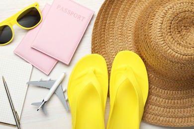 Photo of Time for summer vacation. Toy plane, passports, stationery and beach accessories on light wooden table, flat lay