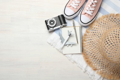 Photo of Time for summer vacation. Toy plane, stationery, shoes, camera and beach accessories on light wooden table, flat lay. Space for text