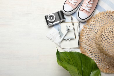 Photo of Time for summer vacation. Toy plane, stationery, shoes, camera, green leaf and beach accessories on light wooden table, flat lay. Space for text