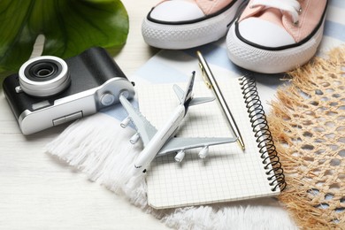Photo of Time for summer vacation. Toy plane, stationery, shoes, camera, green leaf and beach accessories on light wooden table, closeup