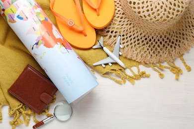 Photo of Time for summer vacation. World map, toy plane, purse, magnifying glass and beach accessories on light wooden table, flat lay. Space for text