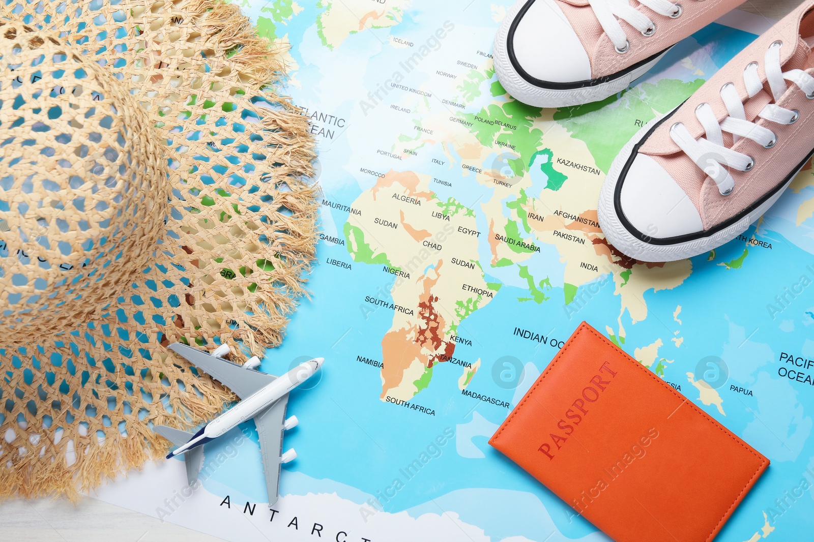 Photo of Time for summer vacation. Toy plane, passport, shoes and straw hat on world map, flat lay