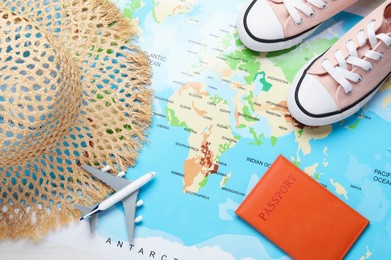 Photo of Time for summer vacation. Toy plane, passport, shoes and straw hat on world map, flat lay