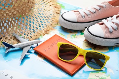 Photo of Time for summer vacation. Toy plane, passport, shoes and beach accessories on world map, closeup