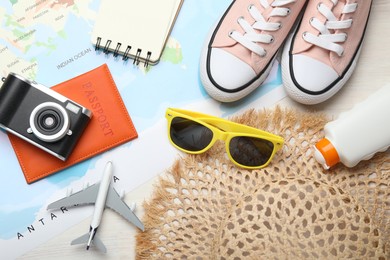Photo of Time for summer vacation. World map, toy plane, passport, camera, notebook, shoes and beach accessories on light wooden table, flat lay
