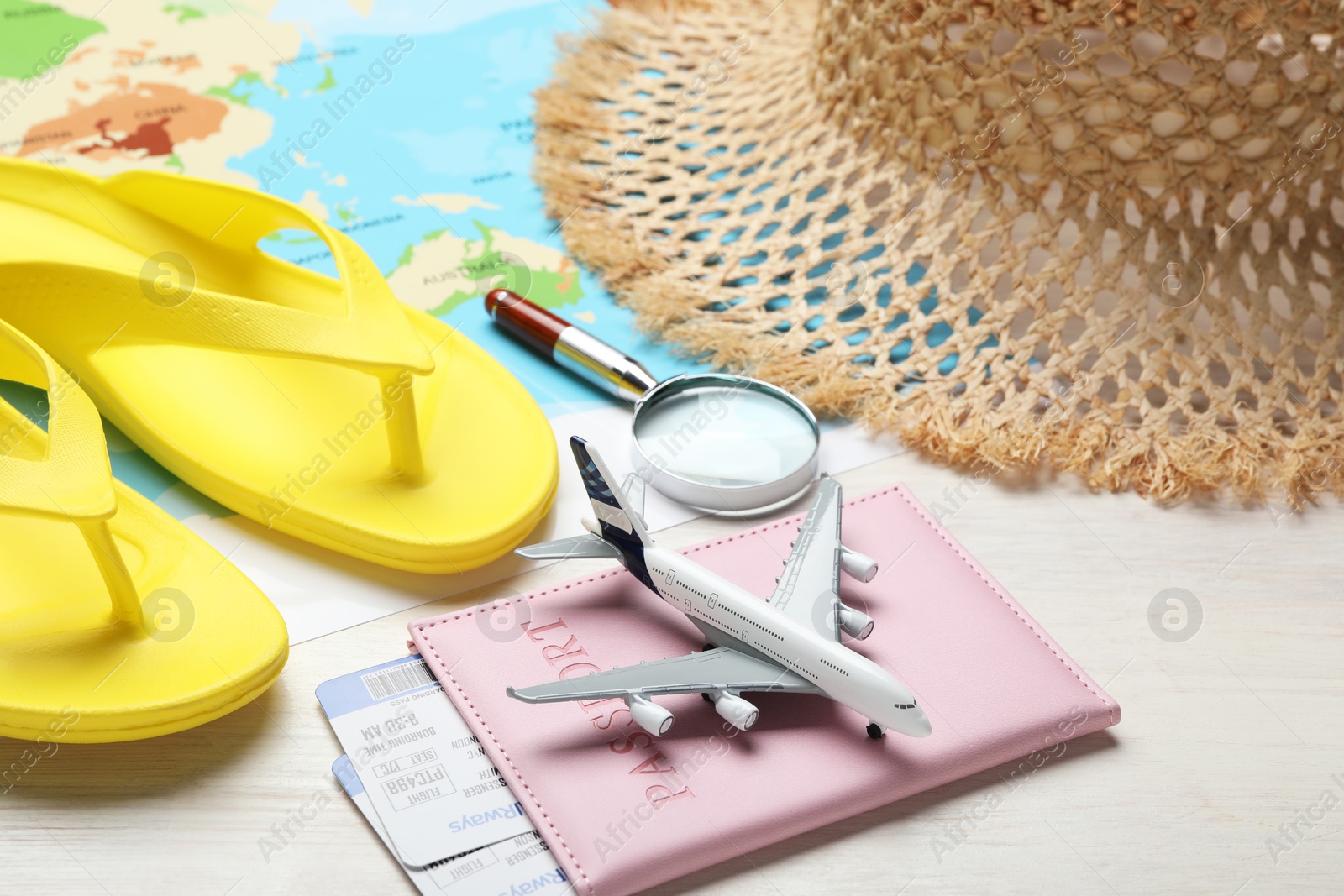 Time for summer vacation. World map, toy plane, passport, flight tickets, magnifying glass and beach accessories on light wooden table, closeup Photo of Time for summer vacation. World map, toy plane, passport, flight tickets, magnifying glass and beach accessories on light wooden table, closeup