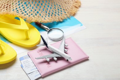 Photo of Time for summer vacation. World map, toy plane, passport, flight tickets, magnifying glass and beach accessories on light wooden table, closeup. Space for text
