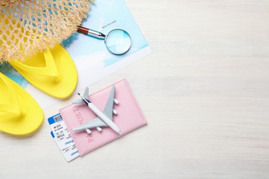 Photo of Time for summer vacation. World map, toy plane, passport, flight tickets, magnifying glass and beach accessories on light wooden table, flat lay. Space for text