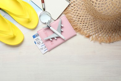 Photo of Time for summer vacation. World map, toy plane, passport, flight tickets, notebook, magnifying glass and beach accessories on light wooden table, flat lay. Space for text