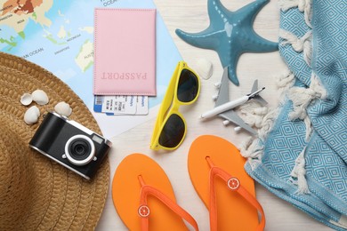 Photo of Time for summer vacation. World map, toy plane, passport, flight tickets, camera and beach accessories on light wooden table, flat lay