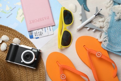 Photo of Time for summer vacation. World map, toy plane, passport, flight tickets, camera and beach accessories on light wooden table, flat lay