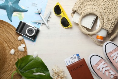 Photo of Time for summer vacation. World map, toy plane, passport, flight tickets, camera, shoes, green leaf and beach accessories on light wooden table, flat lay. Space for text