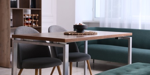 Photo of Wooden table with chairs, bench and decor in dining room. Interior design