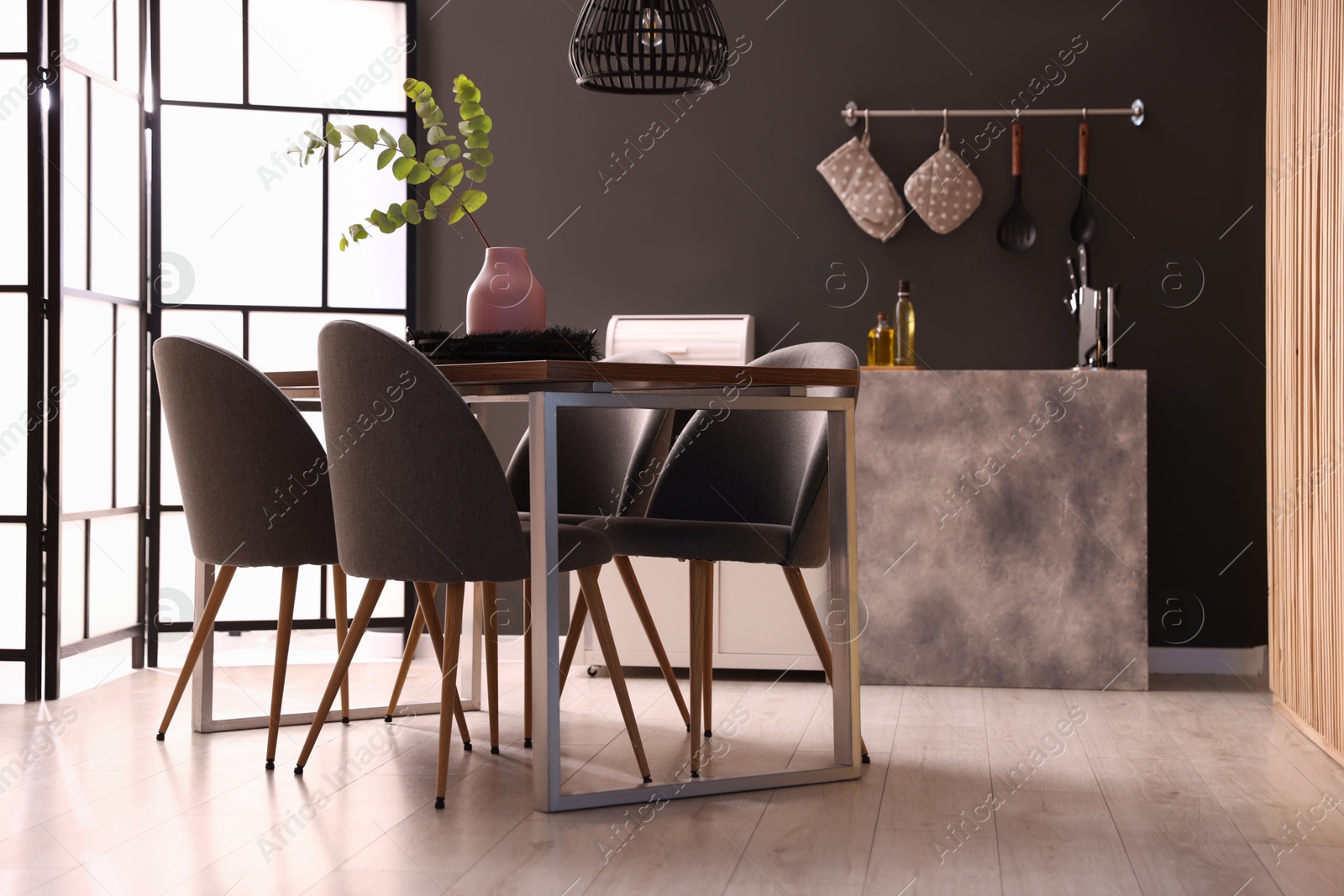 Photo of Wooden table with chairs and floral decor in dining room. Interior design