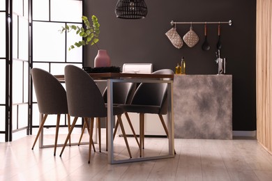 Photo of Wooden table with chairs and floral decor in dining room. Interior design