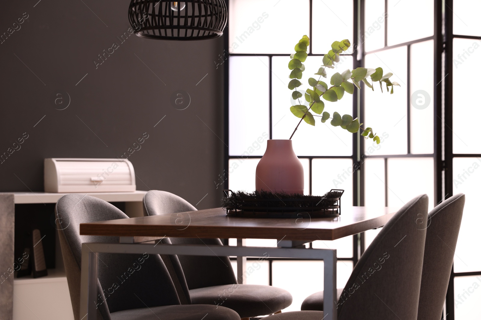 Wooden table with chairs and floral decor in dining room. Interior design Photo of Wooden table with chairs and floral decor in dining room. Interior design