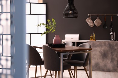 Photo of Wooden table with chairs and floral decor in dining room. Interior design