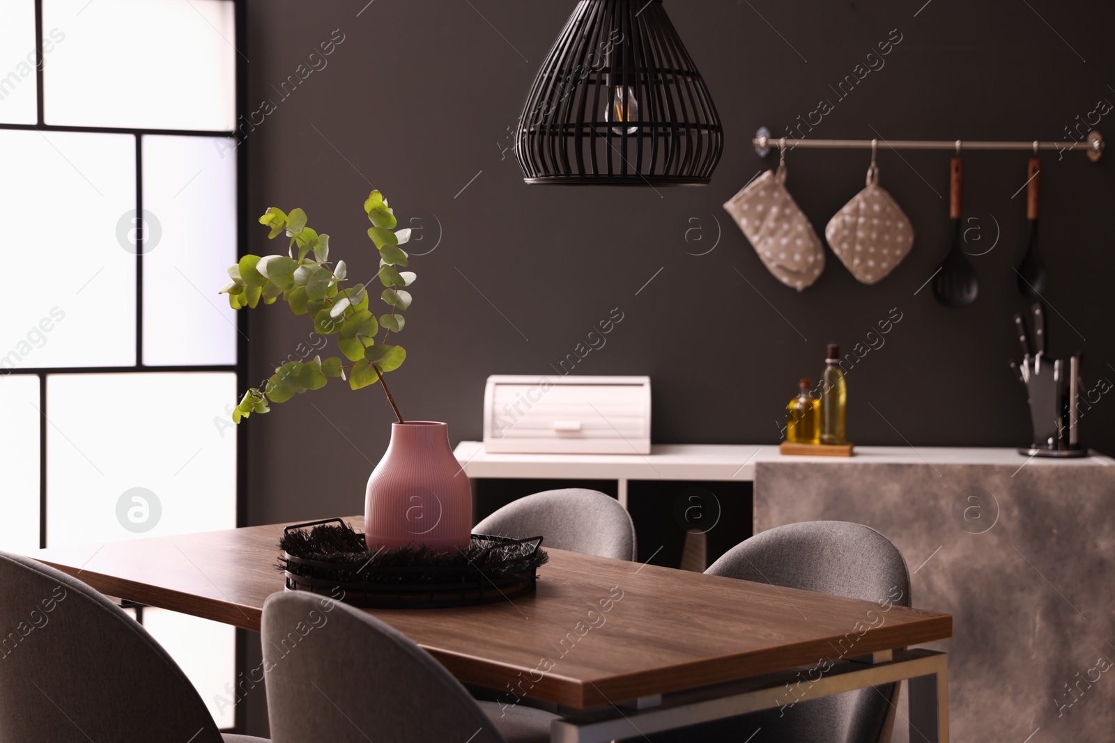 Photo of Wooden table with chairs and floral decor in dining room. Interior design
