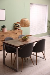 Photo of Wooden table with chairs and apples in dining room. Interior design