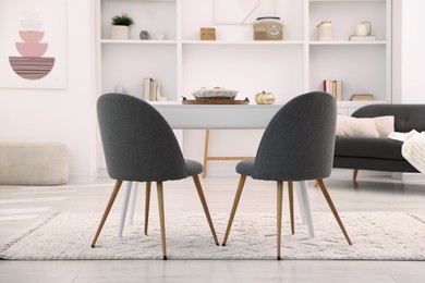 Photo of White table with chairs and decor in stylish dining room. Interior design