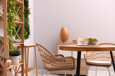 Photo of Wooden table with chairs and decor in stylish dining room. Interior design