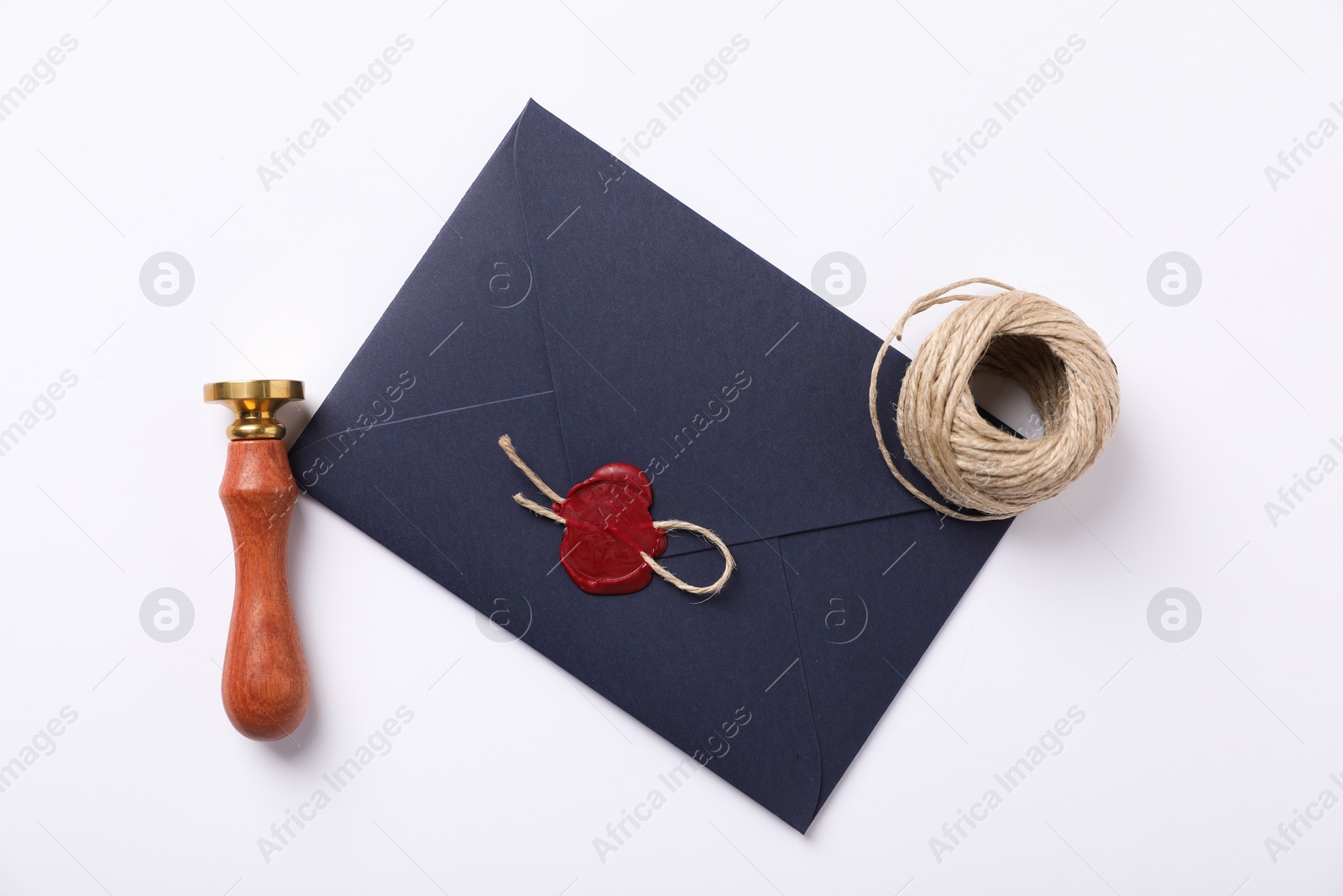 Envelope with wax seal, twine and stamp on white background, flat lay Photo of Envelope with wax seal, twine and stamp on white background, flat lay