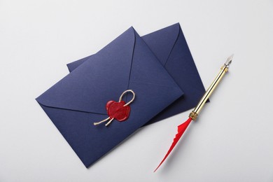 Photo of Envelopes with wax seal, twine and fountain pen on white background, flat lay