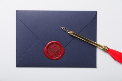 Photo of Envelope with wax seal and fountain pen on white background, top view