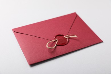 Photo of Envelope with wax seal and twine on white background, closeup