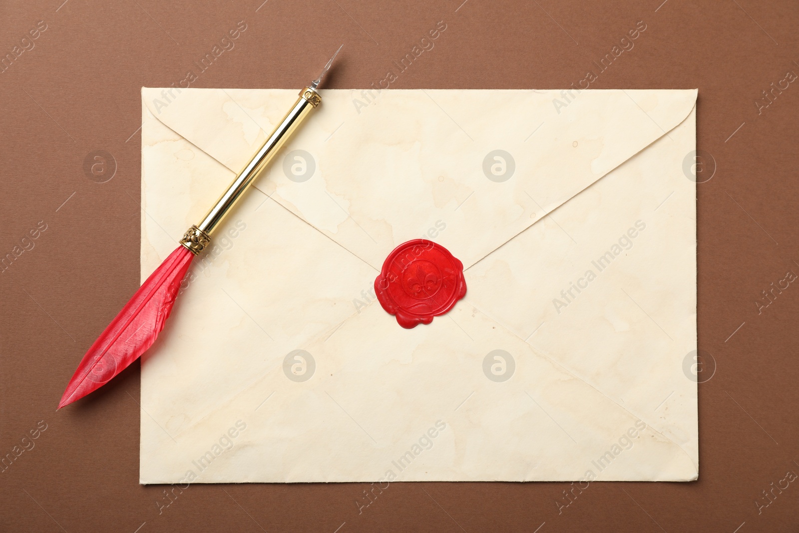 Envelope with wax seal and fountain pen on brown background, top view Photo of Envelope with wax seal and fountain pen on brown background, top view