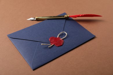 Photo of Envelope with wax seal, twine and fountain pen on brown background
