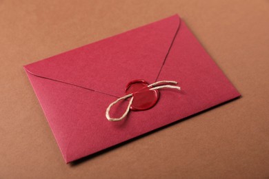 Photo of Envelope with wax seal and twine on brown background, closeup