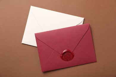 Photo of Envelopes with wax seal on brown background, top view