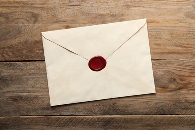 Photo of Envelope with wax seal on wooden table, top view