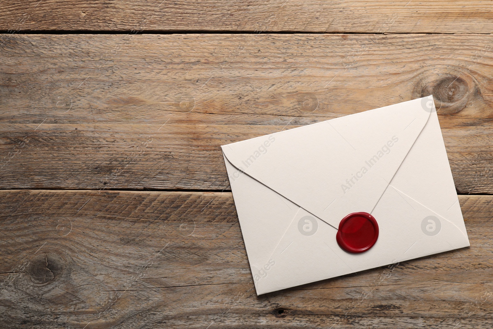 Envelope with wax seal on wooden table, top view. Space for text Photo of Envelope with wax seal on wooden table, top view. Space for text