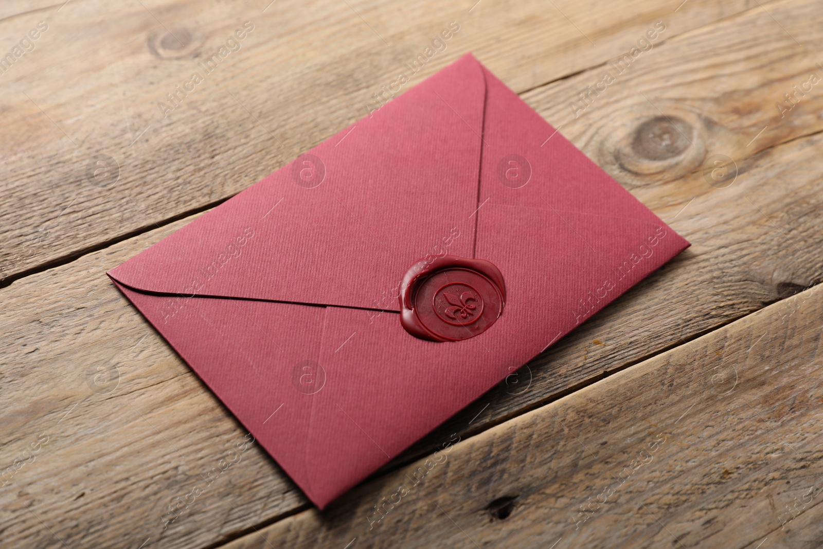 Envelope with wax seal on wooden table, above view Photo of Envelope with wax seal on wooden table, above view