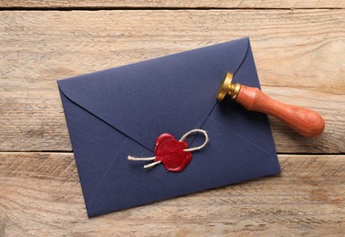 Photo of Envelope with wax seal, twine and stamp on wooden table, flat lay