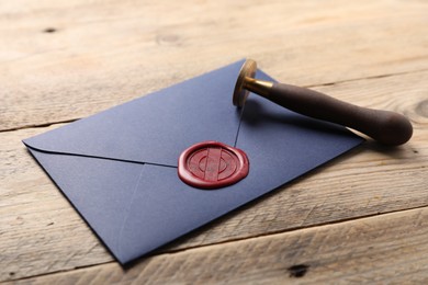 Photo of Envelope with wax seal and stamp on wooden table, closeup