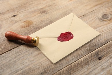 Photo of Envelope with wax seal and stamp on wooden table, closeup