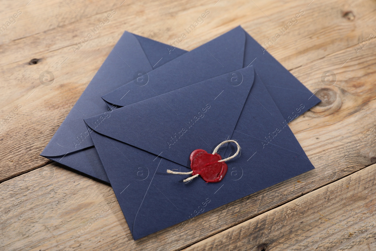 Envelopes with wax seal and twine on wooden table Photo of Envelopes with wax seal and twine on wooden table