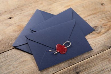 Photo of Envelopes with wax seal and twine on wooden table
