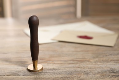 Photo of Wax stamp and envelopes on wooden table, closeup. Space for text
