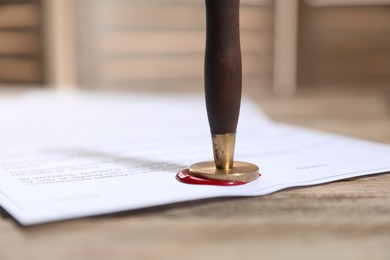 Photo of Documents with wax seal and stamp on wooden table, closeup