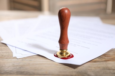 Photo of Documents with wax seal and stamp on wooden table, closeup