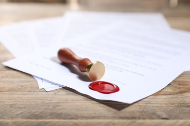 Photo of Documents with wax seal and stamp on wooden table, closeup