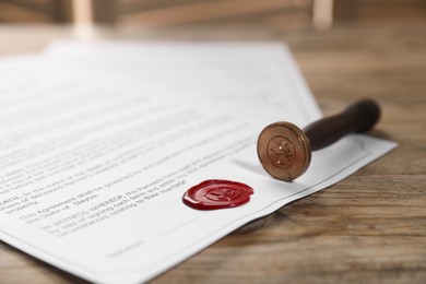 Photo of Documents with wax seal and stamp on wooden table, closeup