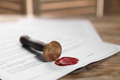 Photo of Documents with wax seal and stamp on wooden table, closeup