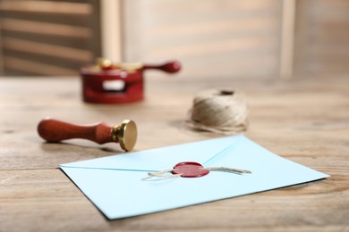 Photo of Envelope with wax seal, twine and stamp on wooden table, closeup