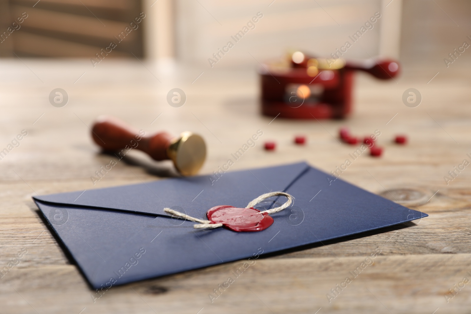 Envelope with wax seal, twine and stamp on wooden table, closeup Photo of Envelope with wax seal, twine and stamp on wooden table, closeup