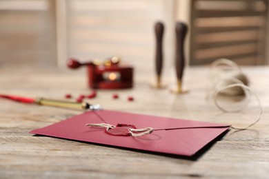 Photo of Envelope with wax seal and twine on wooden table, closeup